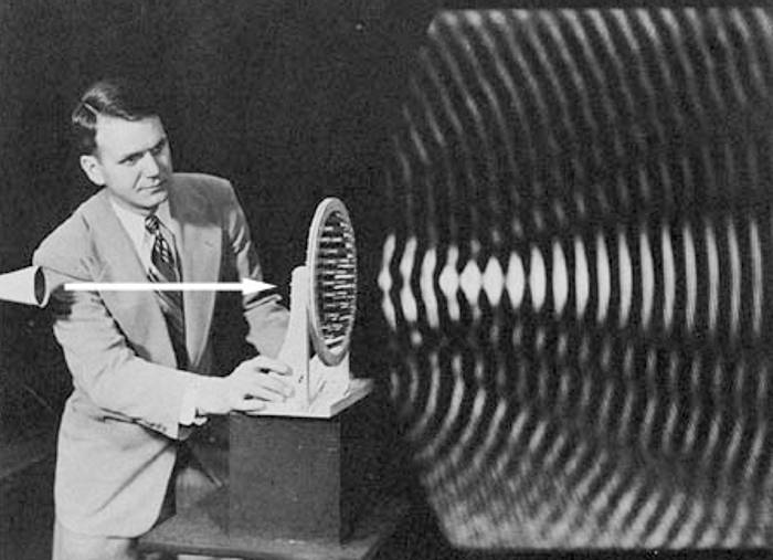 A scientist demonstrating visible waves emanating from a device on a table